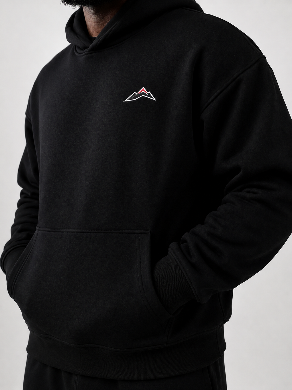 MÒN The Summit Hoodie in black, front view with embroidered mountain logo detail