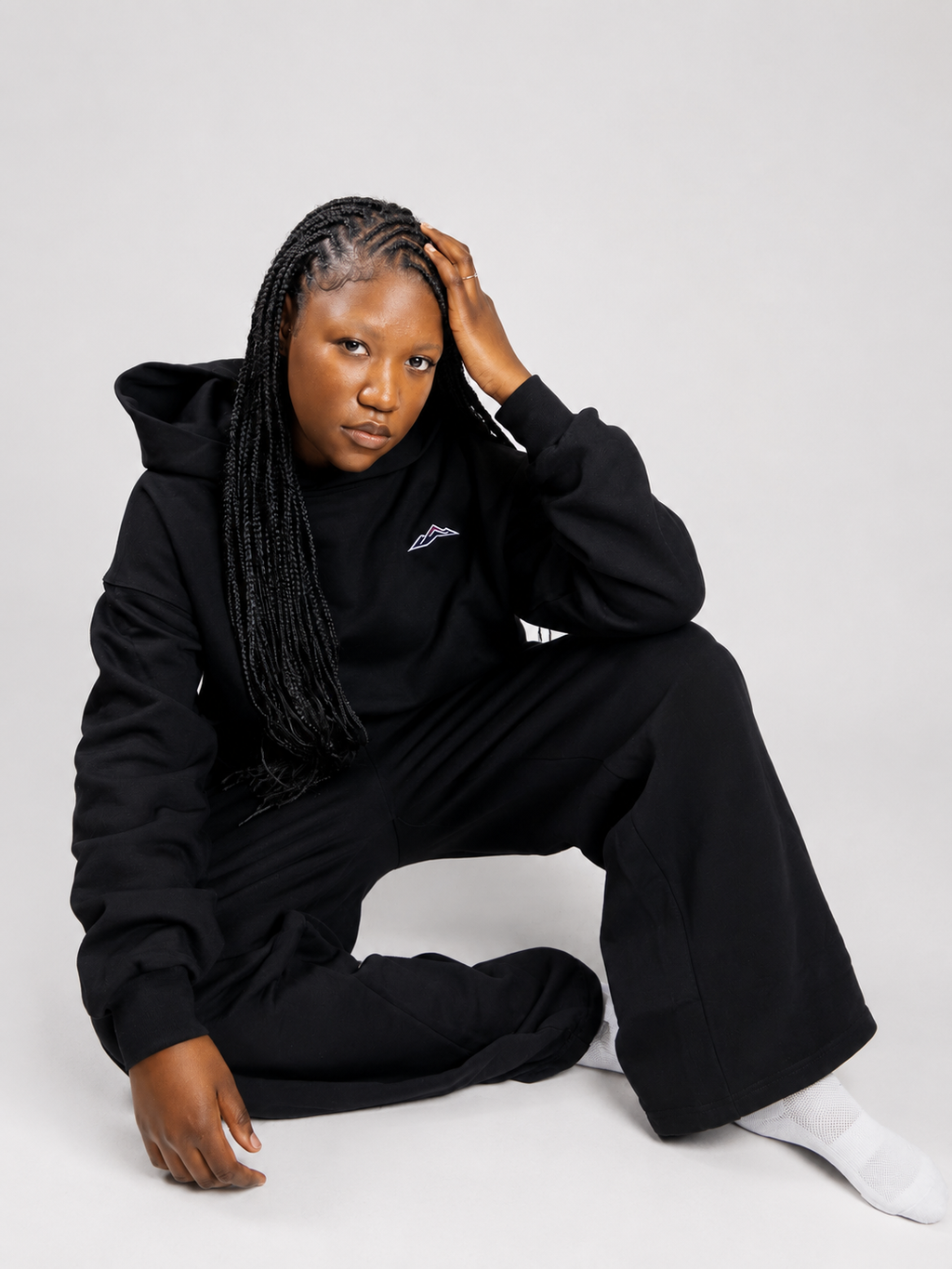 MÒN The Summit Hoodie styled with matching sweatpants, seated lifestyle shot